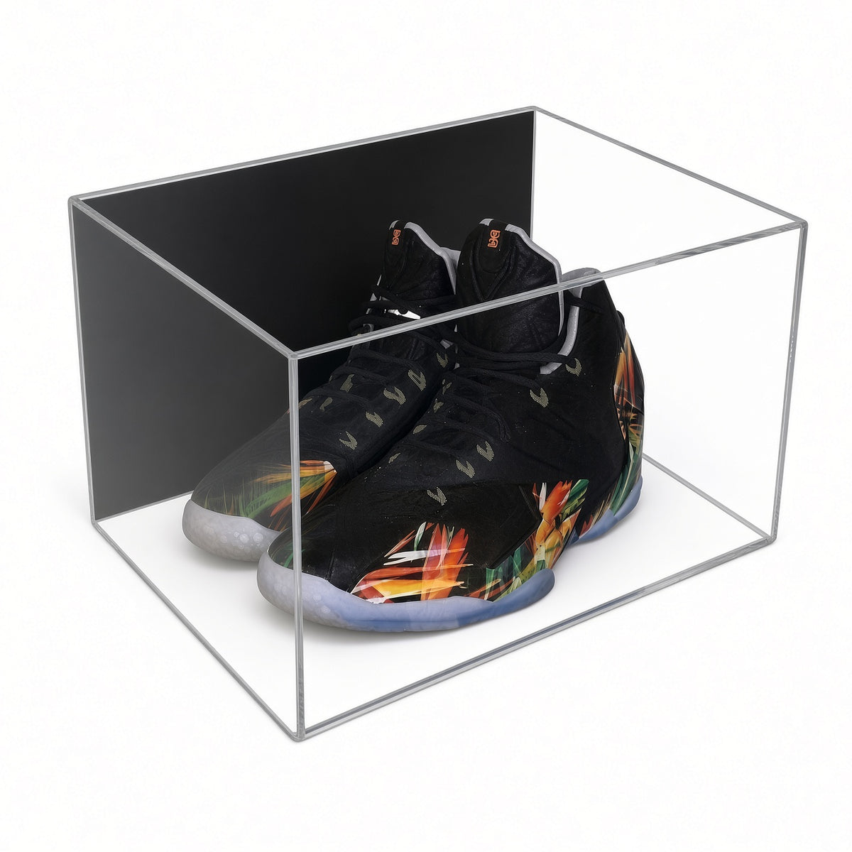 Acrylic wall mount case with a black back holding a pair of black sneakers